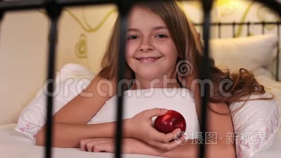 微笑着快乐的女孩在床上吃苹果视频
