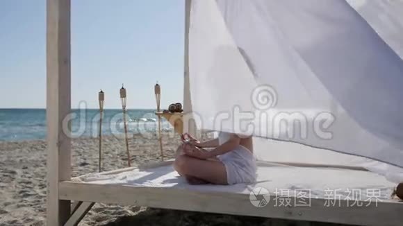 女孩在海滩上打坐，暑假在度假胜地，女人在河堤上做瑜伽，