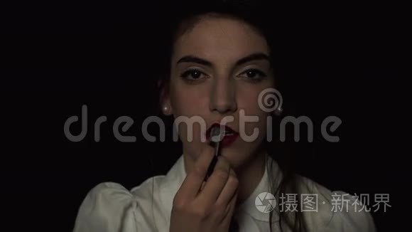 女人用黑色背景的口红涂嘴唇