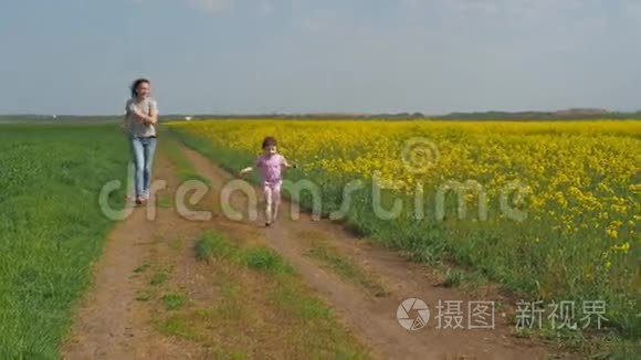 一个有孩子的女人在大自然中玩耍。 一个幸福的家庭正在新鲜的空气中奔跑。 一个带着孩子的女孩沿着一个乡村