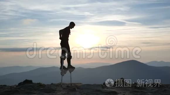 夕阳下，踩着高跷的人走在山顶上。