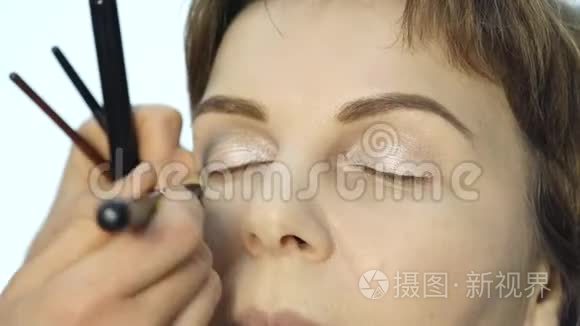 专业化妆师在眼睑上涂眼线的特写。 时尚界化妆品