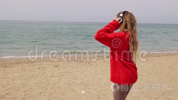 女孩在海边用大耳机听音乐视频
