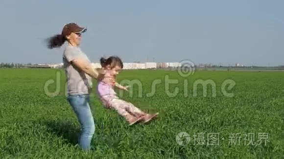 一个女人正在变成一个孩子。 妈妈和女儿在露天玩。 一个女孩带着一个孩子在草地上