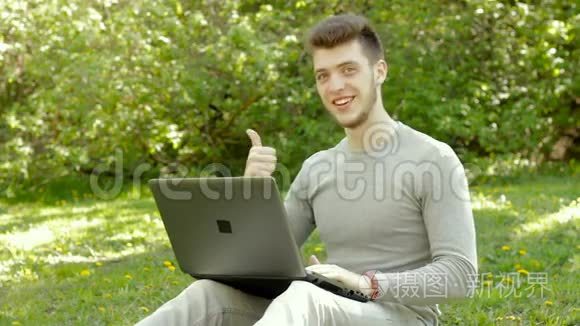 在公园拿着笔记本电脑工作的年轻人竖起大拇指