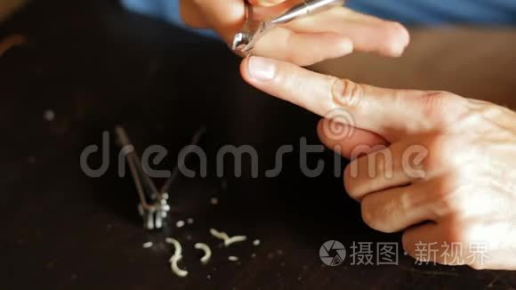 男人的手把指甲周围粗糙的皮肤割下来。用镊子除去角质层。男士美甲