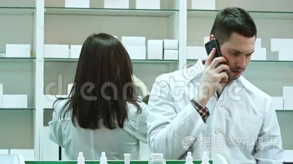 在药房工作的女性和男性药剂师通过智能电话交谈和检查药片
