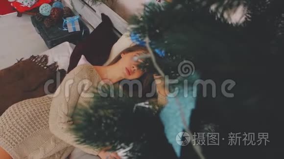 那个女孩躺在圣诞树背景上的床上。 新年