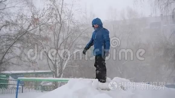 一个孩子跳进冬天公园的雪地里。 暴风雪