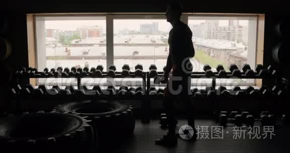 运动员的剪影与哑铃健身室黑色背景，男子与哑铃。 健身。