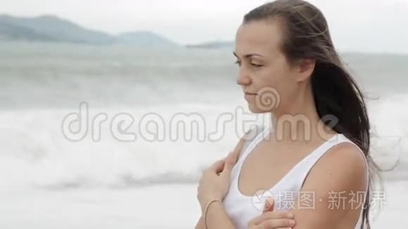 年轻女子站在海滩上，天气不好，看着大海。