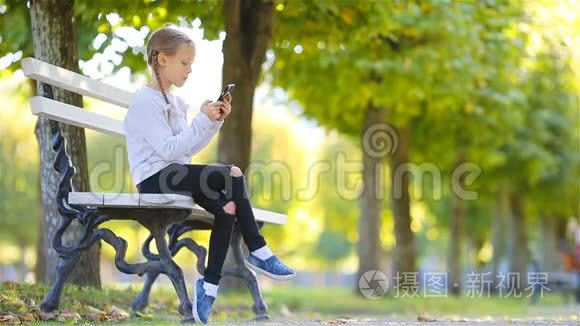 可爱的小女孩在美丽的秋日户外。 秋天的长椅上可爱的孩子