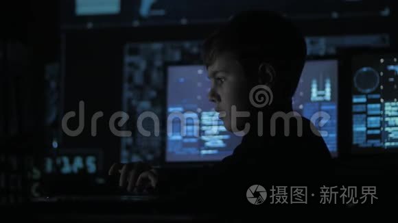 可爱的少年程序员在数据中心的一台电脑上工作，里面装满了显示屏。 神童画像