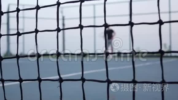 男子网球运动员期待网球在球场上，网在前面。 多莉开。 慢动作