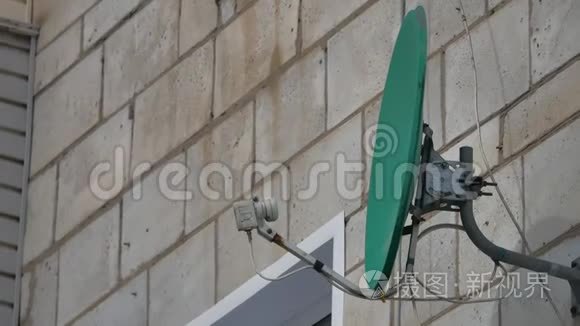 卫星贴在房子的墙上。 挂在房子上的绿色卫星碟