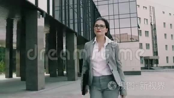 年轻自信的女商人拿着文件正走向办公室