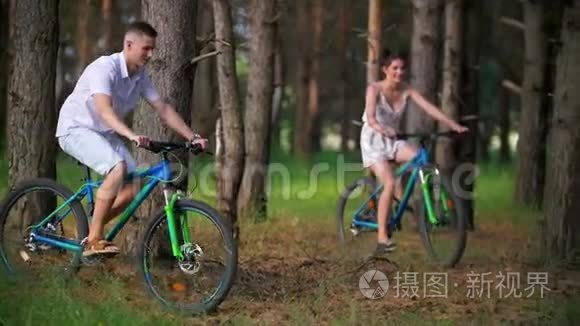 年轻男女骑着自行车穿过松林视频