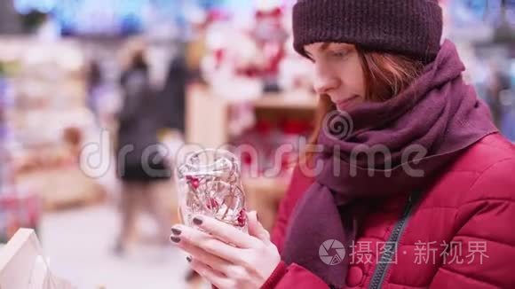 一位年轻的美女在商店里走来走去，挑选圣诞装饰品和装饰品来庆祝新年和圣诞节