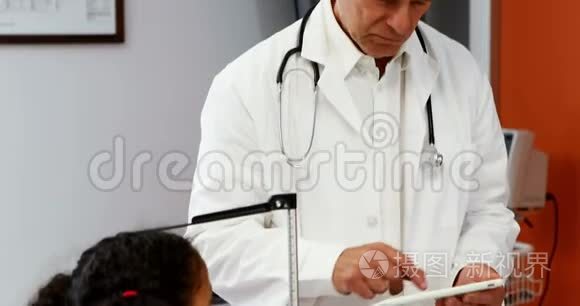 男性医生在测量女孩身高时使用数码平板电脑