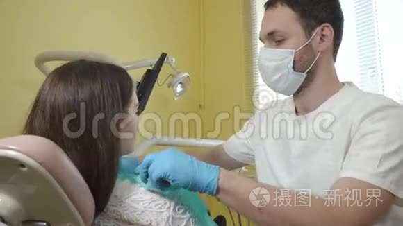 男性牙医准备在牙科诊所检查一名女性病人，穿上胸部无菌布。