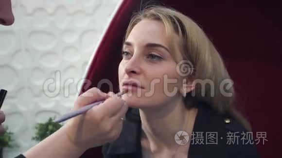 美丽的金发女人在嘴唇上化妆的特写肖像。