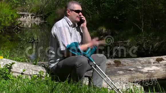 拄拐的残疾人在河边打智能电话视频