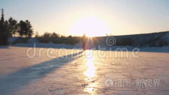 特写，低角度视角快乐的女人在当地公园冰冻的池塘上快速滑冰，在金色的日落下，在神奇的圣诞节