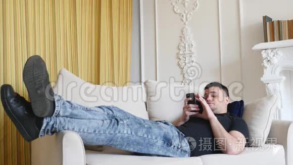 一个用智能手机的人躺在沙发上