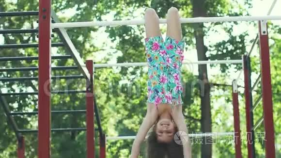 小有趣的女孩倒挂在水平杆上。 慢动作