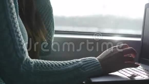 女性手在火车上的笔记本电脑键盘上打字。 女人在铁路上和朋友聊天。 少女视频的预览图