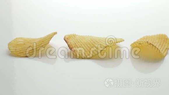 不健康的有害食品，黄色美味的土豆肋条脆片连续躺在白色的桌子背景上，特写镜头移动