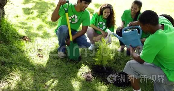 环保人士在公园里给一棵新树浇水