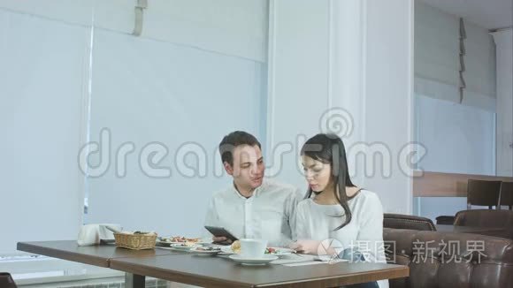 两位同事在咖啡馆吃午饭时讨论工作