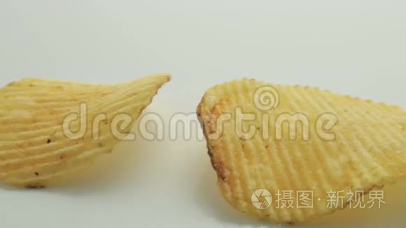 不健康的有害食品，黄色美味的土豆肋条脆片连续躺在白色的桌子背景上，特写镜头移动