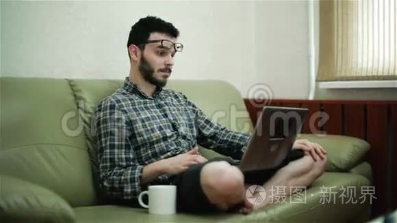戴眼镜的人用笔记本电脑喝咖啡。