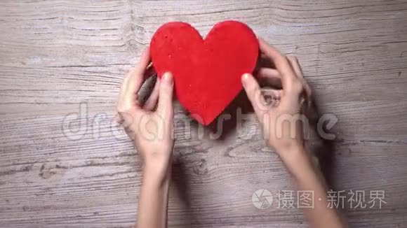 女孩把四颗红心放在一张木桌上，俯视。 花，关怀，爱，情人节的概念.. 4K视频