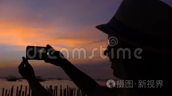 游客在海滩上打着日落电话拍照。 菲律宾