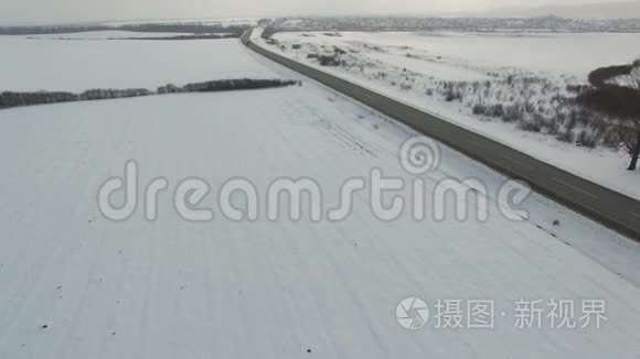 在雪域驾驶冬季道路的卡车和汽车的空中射击。