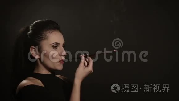 美丽的女人在黑色背景上的喉舌里抽烟