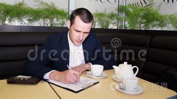 商人坐在咖啡馆里喝咖啡写文件视频