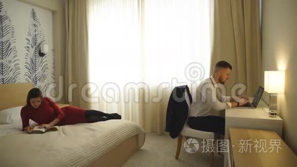 旅馆的房间，电脑的男人，床上看杂志的女孩