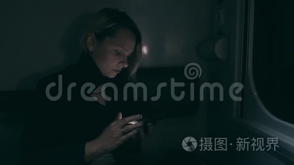 那个女孩晚上在火车上。 坐在火车上用智能手机