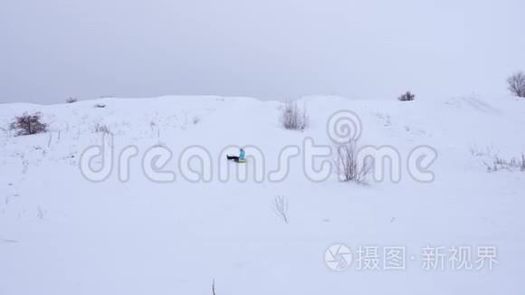 快乐的年轻女孩滑下雪滑到充气雪管上，挥动她的手。 女孩在公园里玩