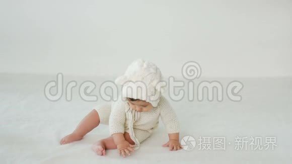 小孩穿着白色的衣服坐在床上