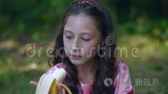 漂亮的小女孩在花园里吃香蕉