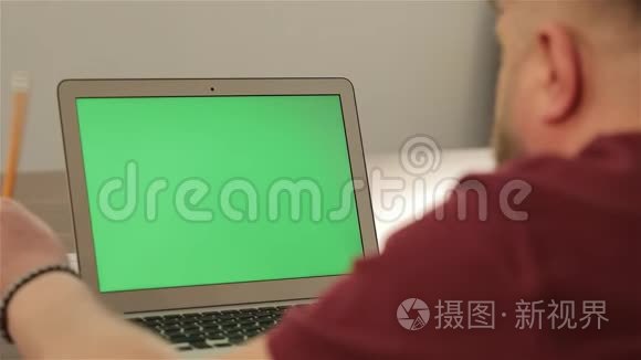 创意经理工作。 商业概念。 自信的年轻人在他的笔记本电脑上用彩色钥匙绿色屏幕