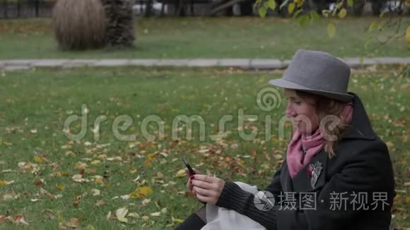 秋天公园里一个戴着帽子的漂亮年轻女人在用手机说话