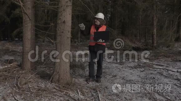 疲惫的伐木工人带着笔记本电脑在森林里