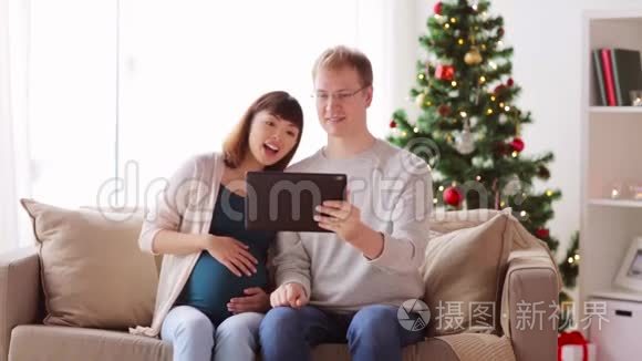 圣诞节带平板电脑的男人和孕妇视频