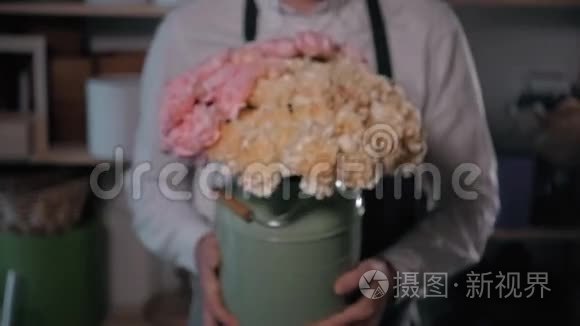 为情人节准备鲜花、玫瑰花、松果和丁香花的花艺人，近距离观看花艺师`工作场所的鲜花。